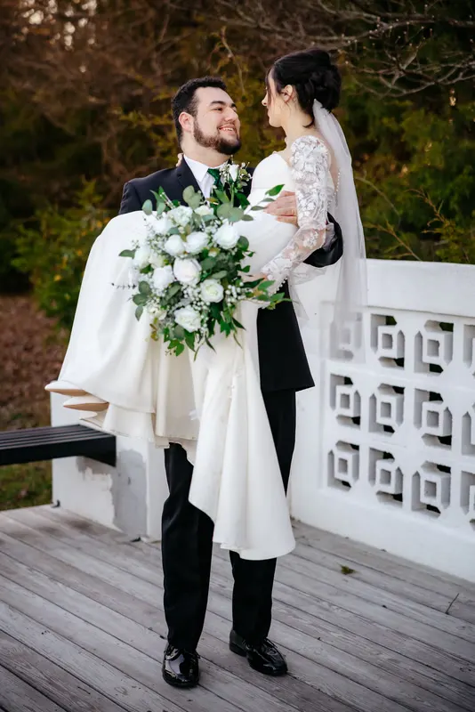Groom holding the bride on a wooden deck